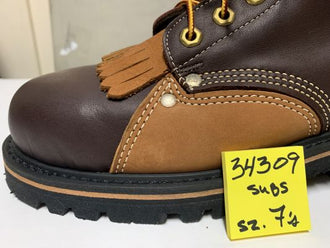 A close-up of a brown and tan leather lace-up boot with a black sole and a yellow handwritten size sticker on the side.